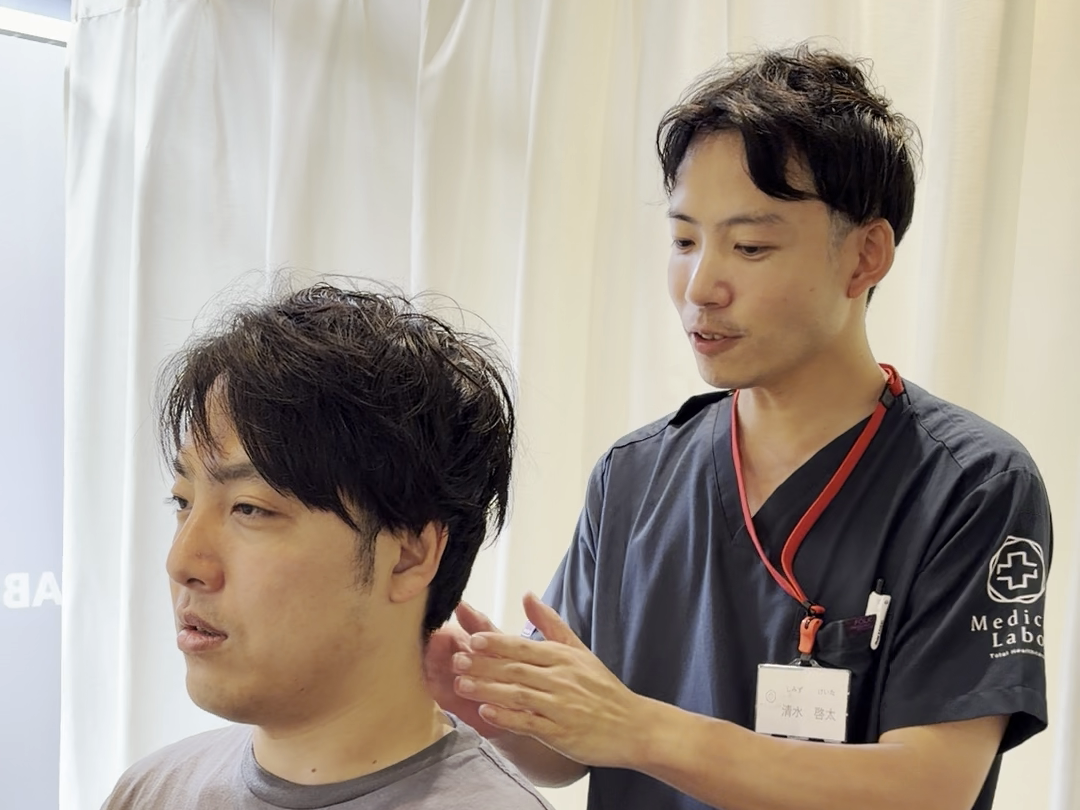 取材時の座位で肩に手を添える場面