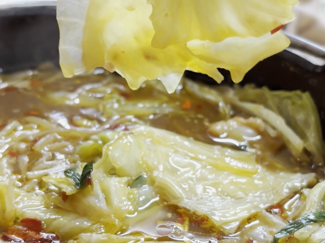 煮えた野菜と具材を箸で持ち上げる